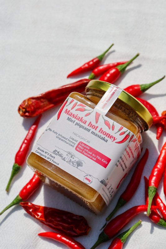 Masiaka hot honey jar surrounded by red chili peppers