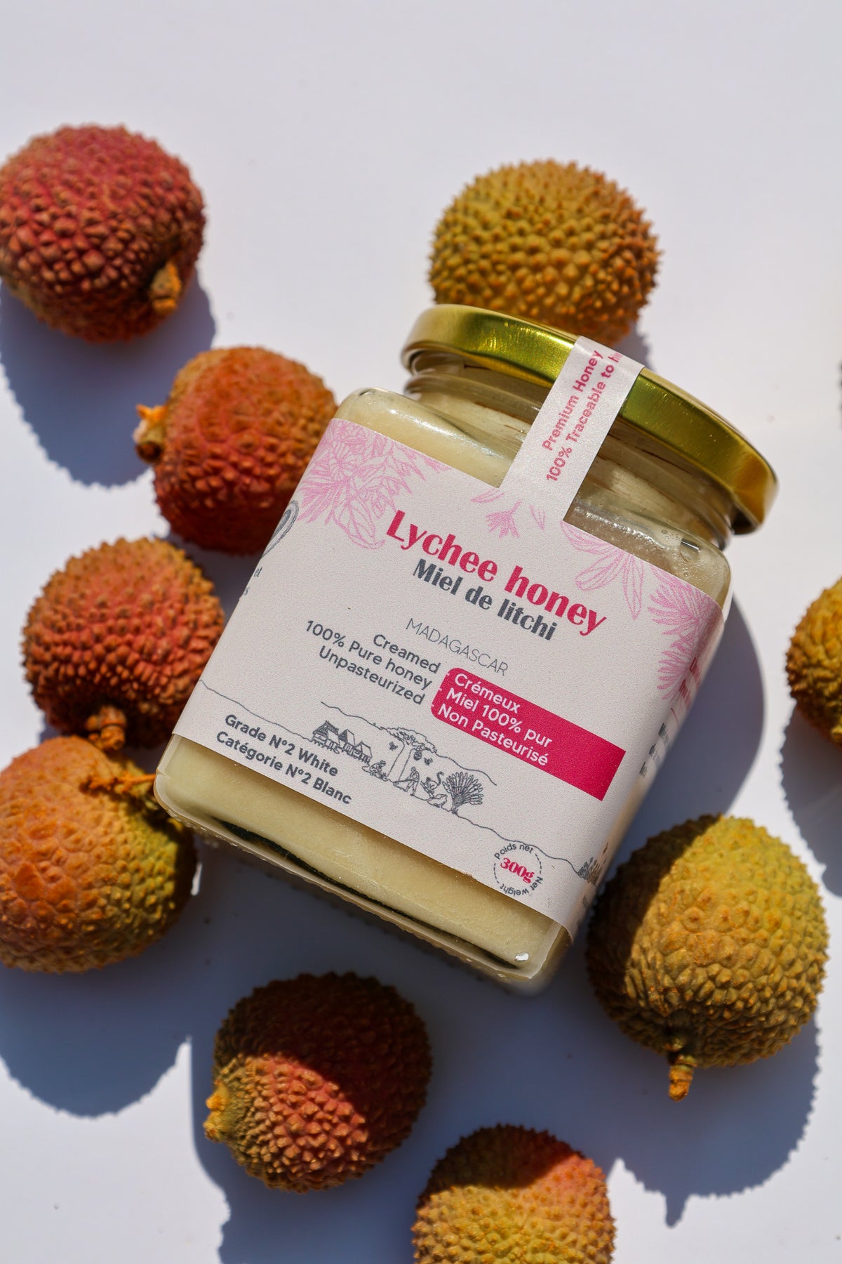 Lychee honey jar lying on its side surrounded by fresh lychees