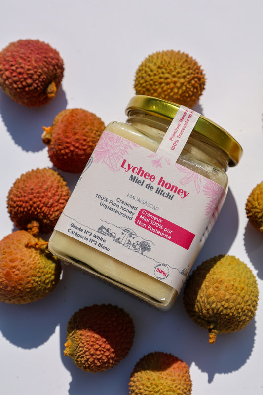Lychee honey jar lying on its side surrounded by fresh lychees