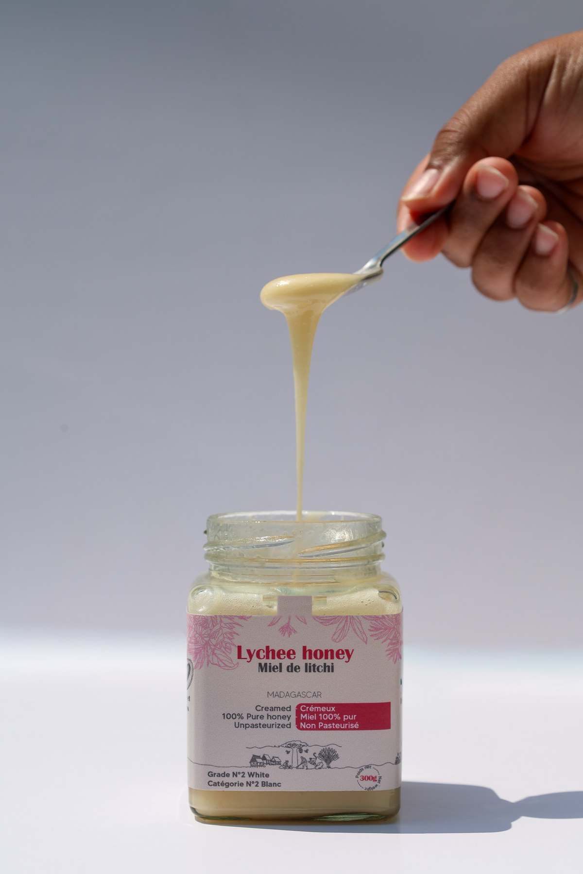 Lychee honey dripping from a spoon into a jar